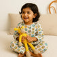 Child holding a yellow toy giraffe on a bed