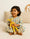 Child holding a yellow toy giraffe on a bed