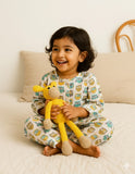 Child holding a yellow toy giraffe on a bed